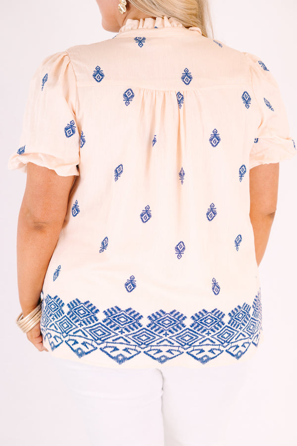 Chic Soul plus size clothing, Beige short-sleeve blouse with a relaxed, flowy fit, featuring blue embroidered geometric patterns, a ruffled split neckline with tie tassels, and a decorative blue border along the hem.