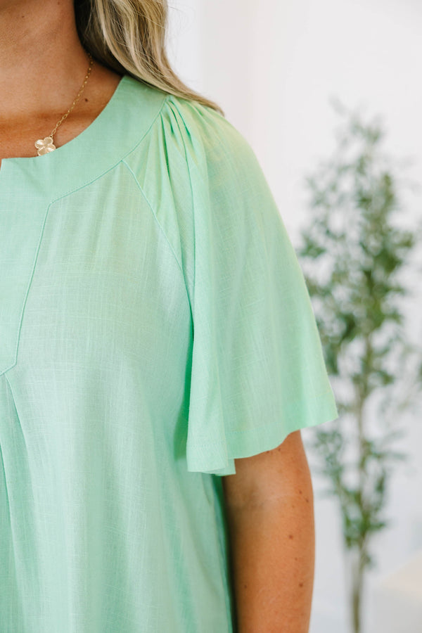 Plus size mint green flowy top with a split neckline and short flutter sleeves.