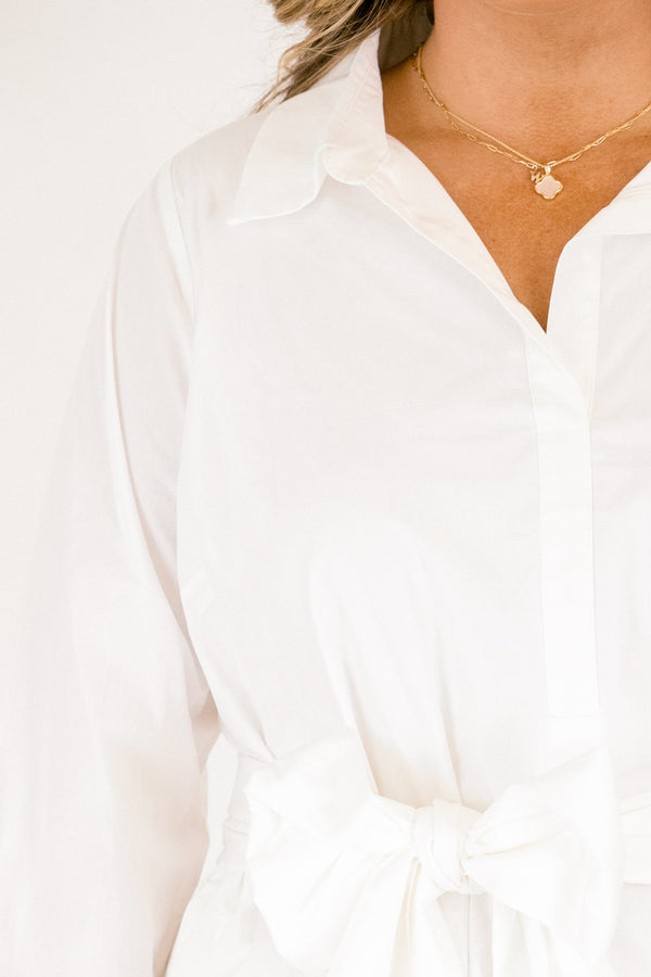 Chic Soul plus size clothing,  white dress with long sleeves a ruffle detail on the bottom of the dress buttons going down to the bottom of the chest and a belt that ties into a bow going around the waist 