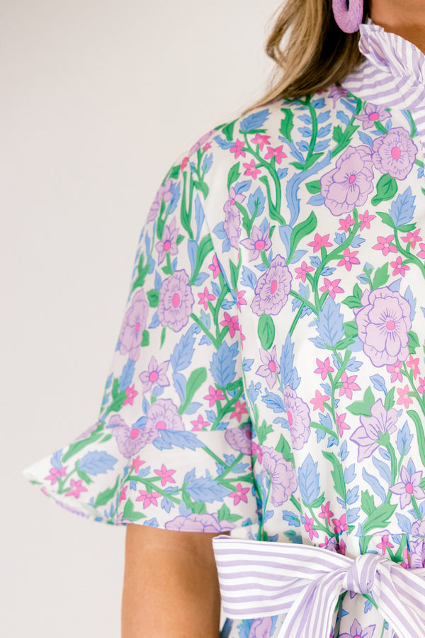 Chic Soul plus size clothing, purple floral midi dress with short sleeves that have a ruffle detail at the bottom of each sleeves as well as a striped purple pattern going down the chest and along the neckline as well as a striped belt that ties around the waist 