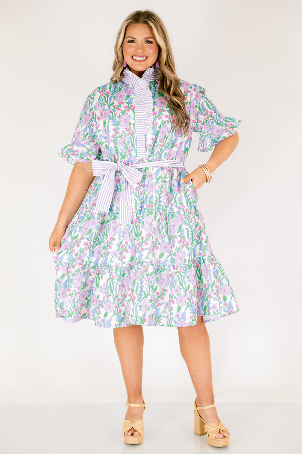Chic Soul plus size clothing, purple floral midi dress with short sleeves that have a ruffle detail at the bottom of each sleeves as well as a striped purple pattern going down the chest and along the neckline as well as a striped belt that ties around the waist 