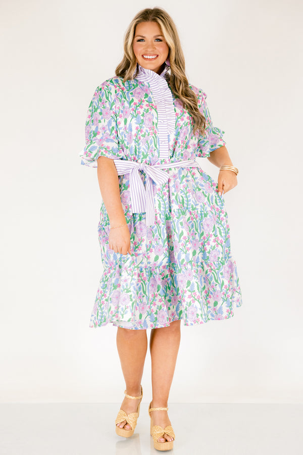 Chic Soul plus size clothing, purple floral midi dress with short sleeves that have a ruffle detail at the bottom of each sleeves as well as a striped purple pattern going down the chest and along the neckline as well as a striped belt that ties around the waist 