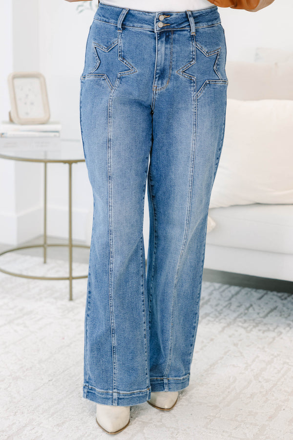 Plus Size medium wash wide leg jeans with star-shaped stitching on the front pockets and seams.