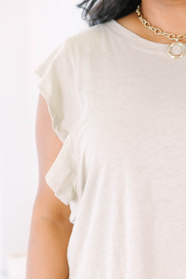 Plus Size light mocha top with a round neckline and ruffled cap sleeves paired with white shorts.