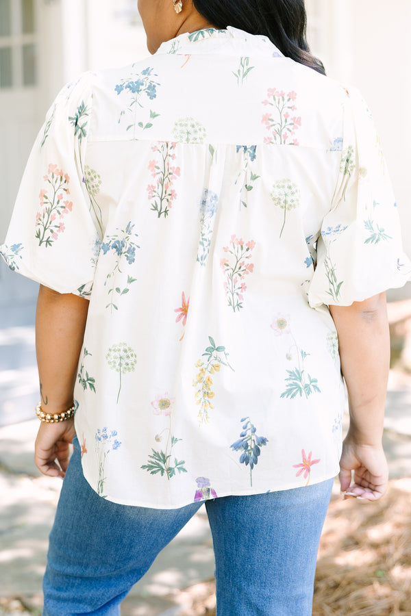Ivory floral blouse with a relaxed fit, featuring a ruffled collar, short puff sleeves, and a lightweight woven fabric with a delicate multicolor botanical print.