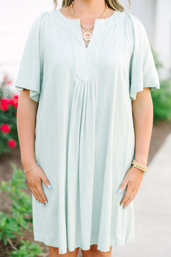 Short sleeve sage green dress with a notched neckline and pleated front detailing.