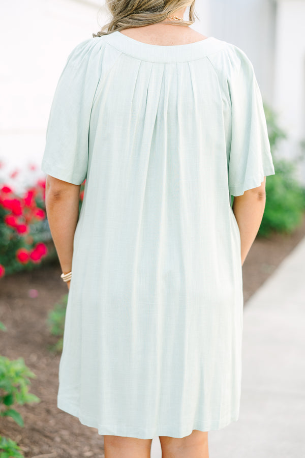 Short-sleeve sage green mini dress with a notched neckline and pleated front detailing.