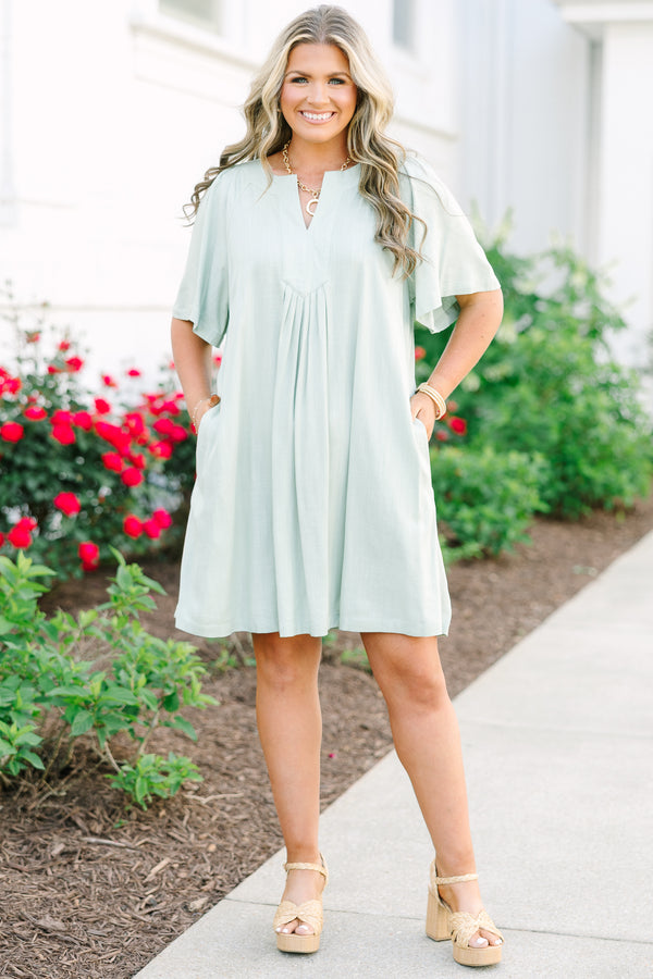 Short-sleeve sage green mini dress with a notched neckline and pleated front detailing.
