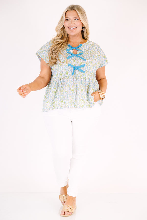 Chic Soul plus size clothing, teal short sleeve top with a floral block pattern and three blue bows going down the center of the bust 