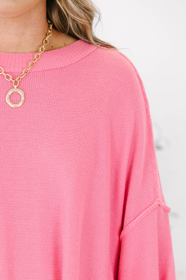Bright pink sweater with a relaxed drop shoulder knit and exposed seams.