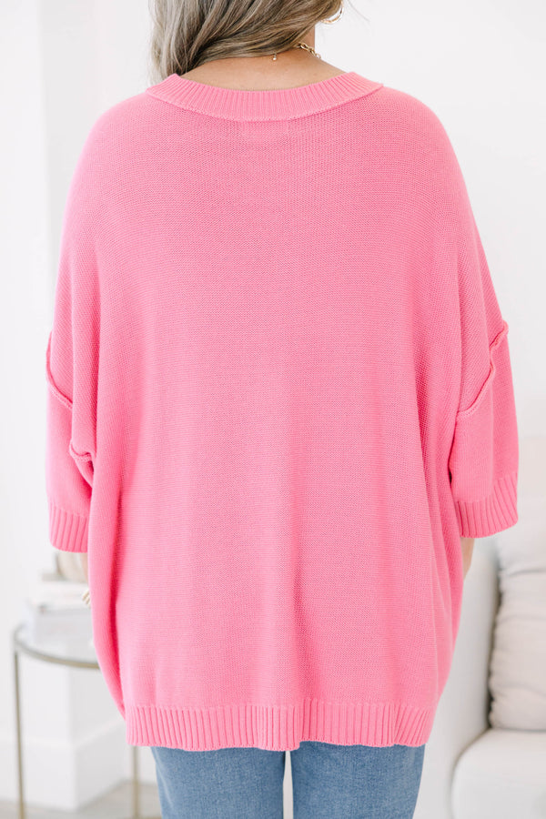 Bright pink sweater with a relaxed drop shoulder knit and exposed seams.