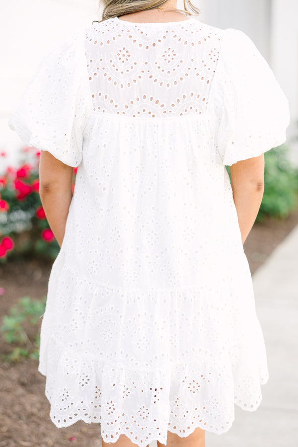 Plus Size white eyelet mini dress with puff sleeves, smocked bodice, and tassel tie neckline.