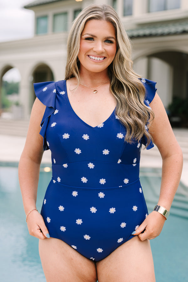 Plus Size navy blue one-piece swimsuit with a white daisy print and ruffled cap sleeves.