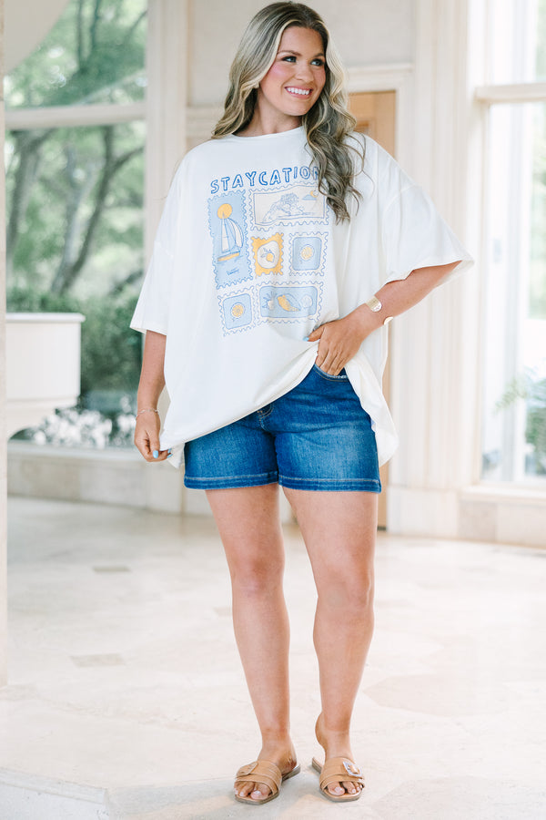 Plus Size ivory boyfriend tee with a blue and yellow staycation stamp graphic and denim shorts.