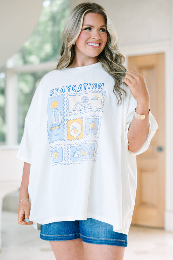 Plus Size ivory boyfriend tee with a blue and yellow staycation stamp graphic and denim shorts.