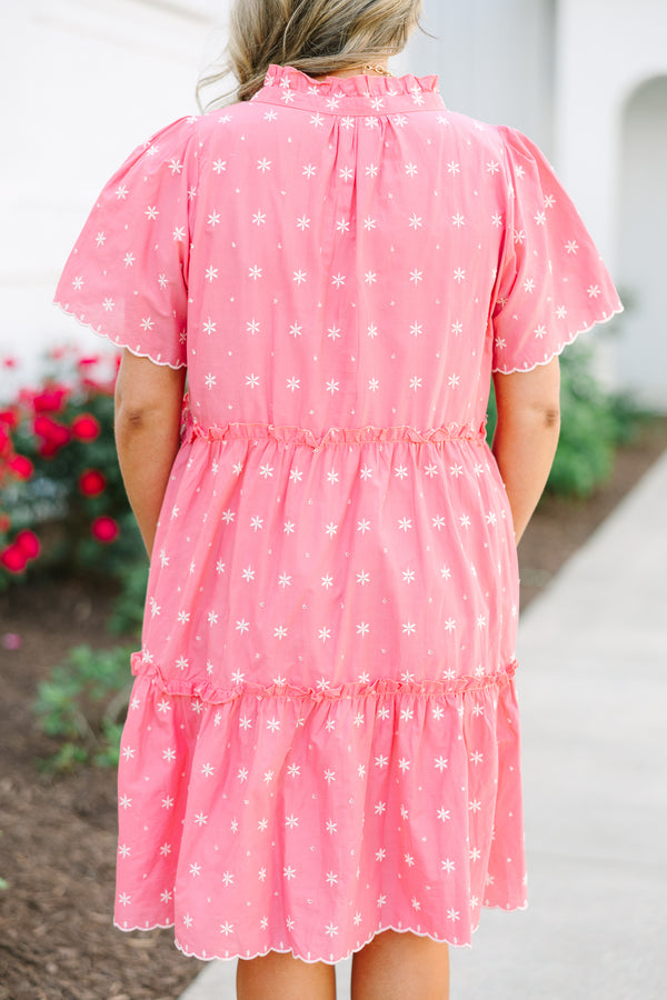 Pink tiered shift dress with white floral embroidery, short flutter sleeves, and a ruffled collar.