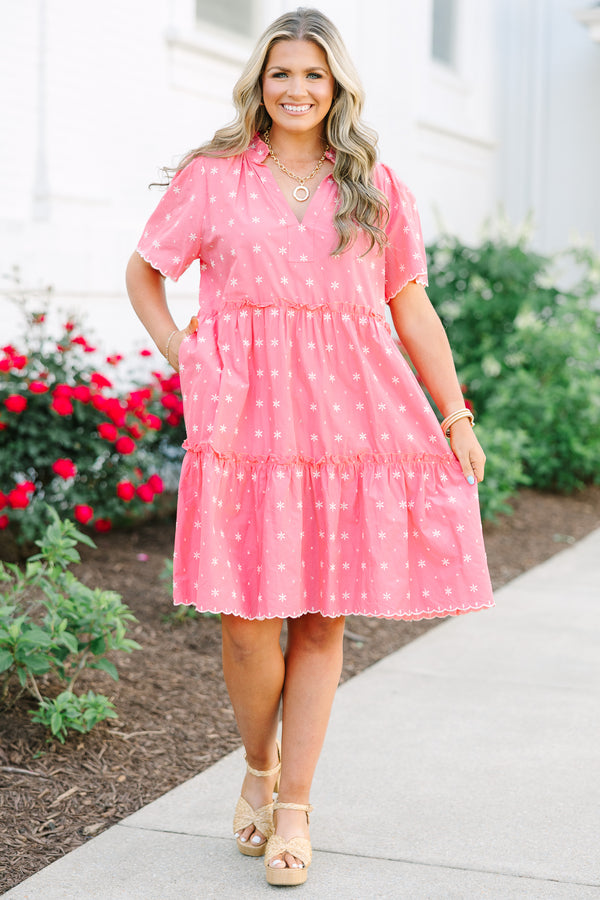 Pink tiered shift dress with a split neckline, short sleeves, and white floral embroidery.
