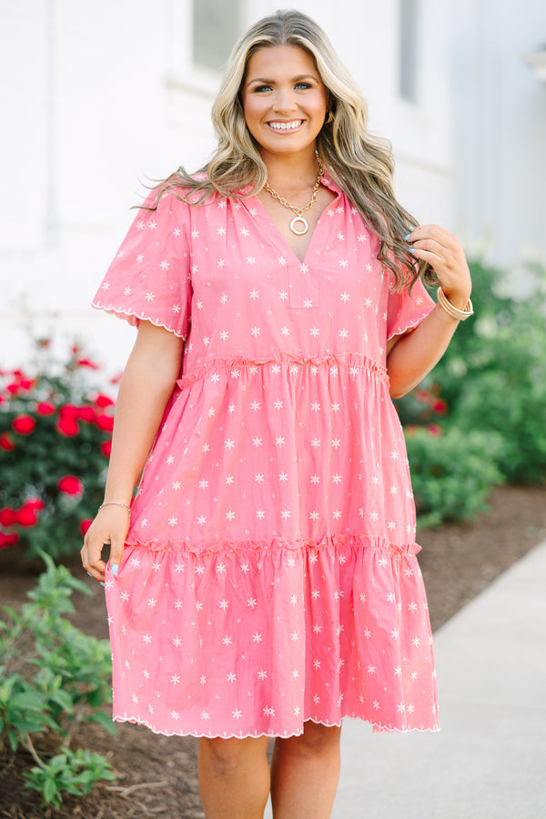Pink tiered shift dress with a split neckline, short sleeves, and white floral embroidery.