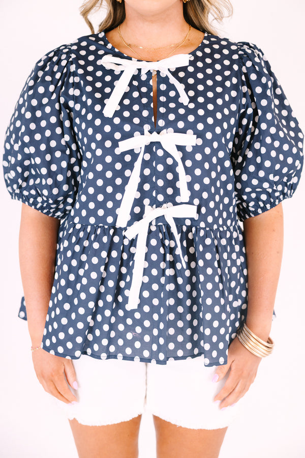 Chic soul plus size clothing, navy top with white polka dots and bubble sleeves as well as three white bows going down the center of the top 
