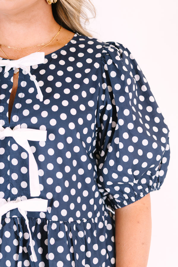 Chic soul plus size clothing, navy top with white polka dots and bubble sleeves as well as three white bows going down the center of the top 
