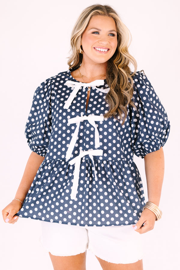 Chic soul plus size clothing, navy top with white polka dots and bubble sleeves as well as three white bows going down the center of the top 
