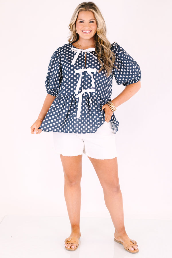 Chic soul plus size clothing, navy top with white polka dots and bubble sleeves as well as three white bows going down the center of the top 

