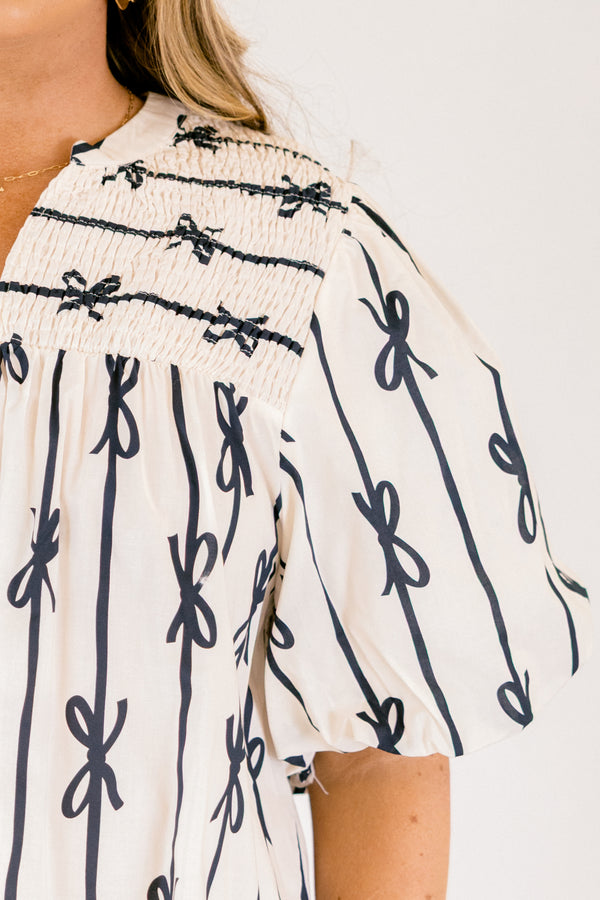 Chic Soul plus size clothing, off white short sleeve top with vertical navy blue lines and bows on the top and horizontal navy blue lines and bows along the top with a v-neckline