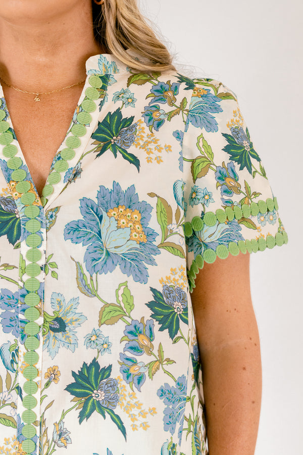 Chic Soul plus size clothing, white short sleeve top with blue and green tropical floral pattern and green dot embroidery along the hems of the sleeves and bordering the v-neckline going down the middle of the top