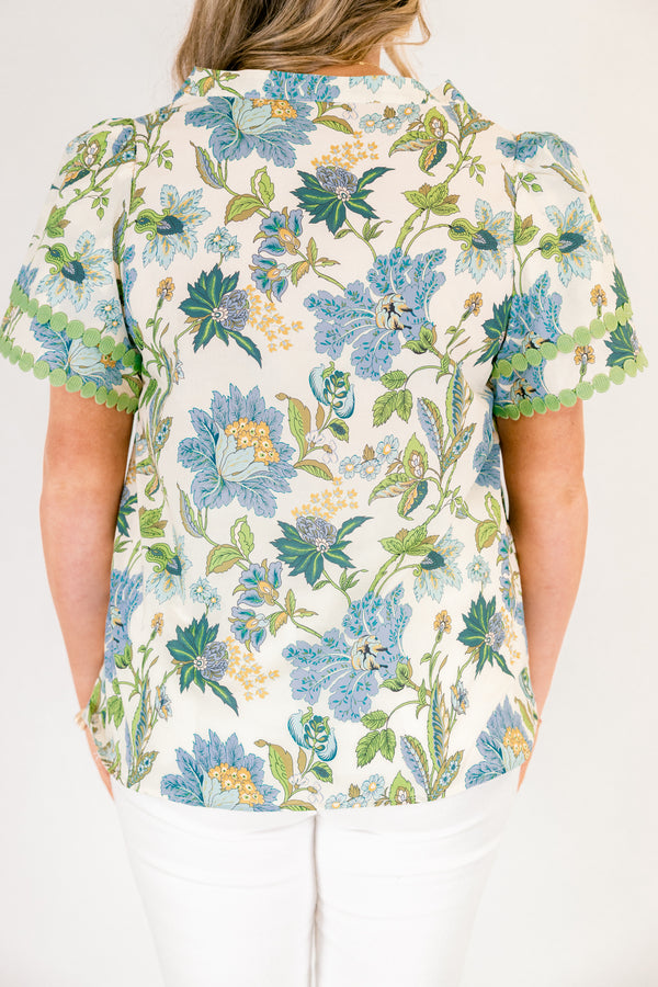 Chic Soul plus size clothing, white short sleeve top with blue and green tropical floral pattern and green dot embroidery along the hems of the sleeves and bordering the v-neckline going down the middle of the top