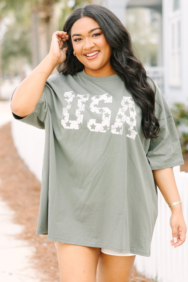 Chic Soul plus size clothing, moss green short sleeve oversized boyfriend tee with “USA” in bold block white font with star cutouts 
