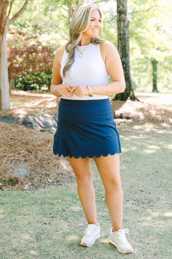Navy skort with a high-rise waistband and smooth stretch fabric, featuring a scalloped hem for a feminine finish.