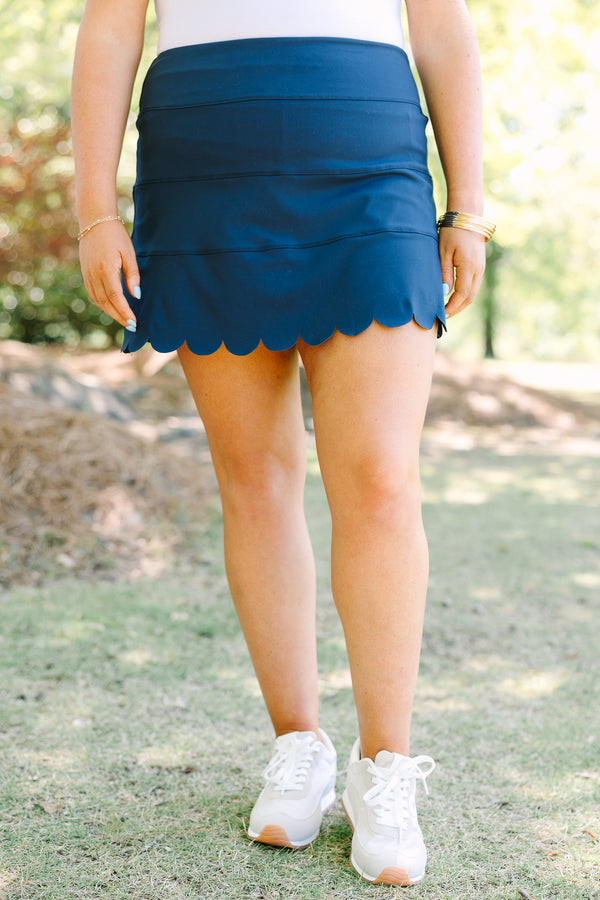 Navy skort with a high-rise waistband and smooth stretch fabric, featuring a scalloped hem for a feminine finish.