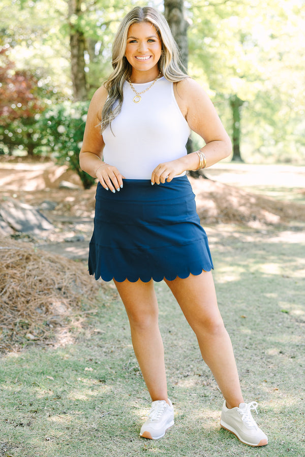 Navy skort with a high-rise waistband and smooth stretch fabric, featuring a scalloped hem for a feminine finish.