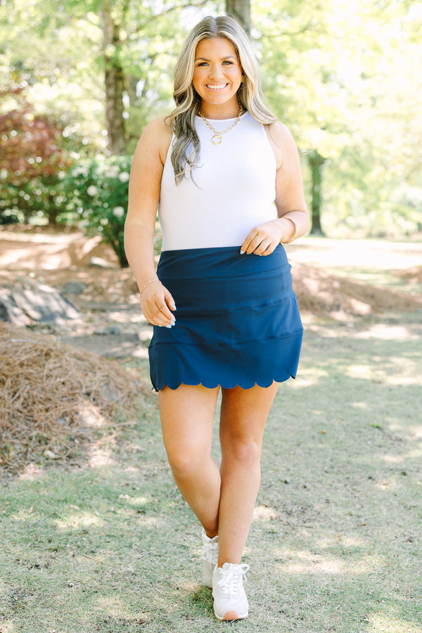 Navy skort with a high-rise waistband and smooth stretch fabric, featuring a scalloped hem for a feminine finish.