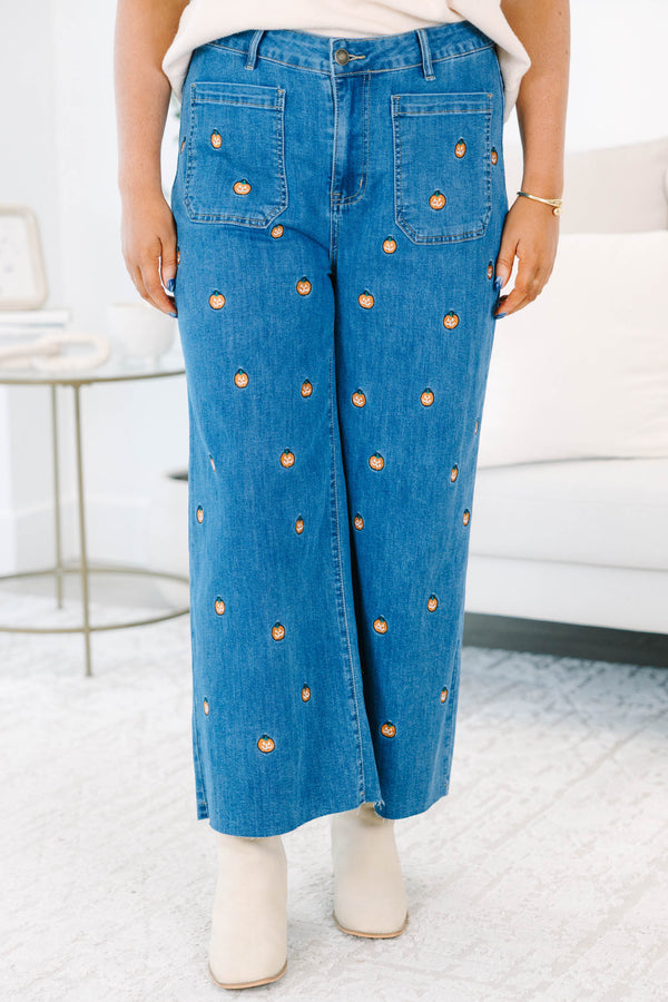 Plus size wide leg blue denim jeans with all-over pumpkin embroidery and a raw hem.