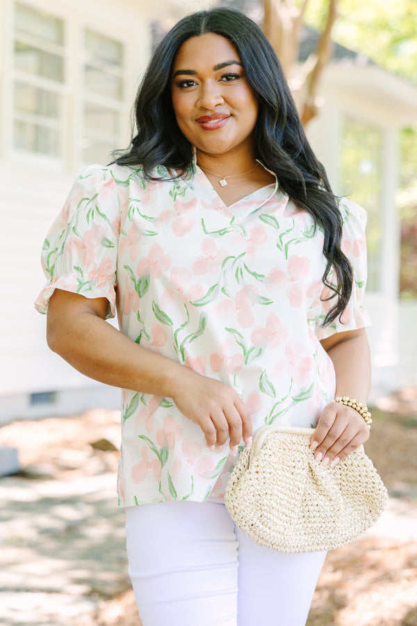 Plus Size pink floral v-neck top with short bubble sleeves and a woven straw clutch.