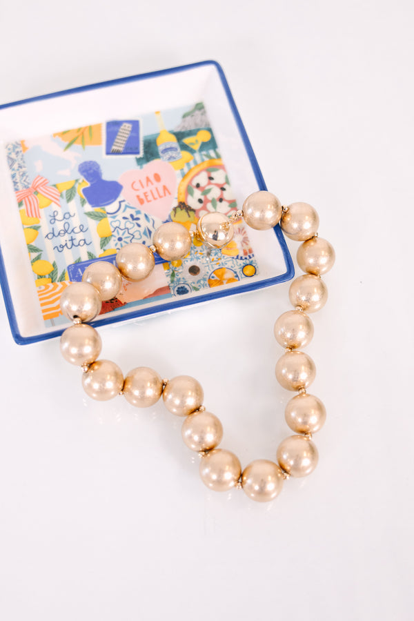 A timeless necklace featuring large, cascading gold statement beads with a warm metallic finish.