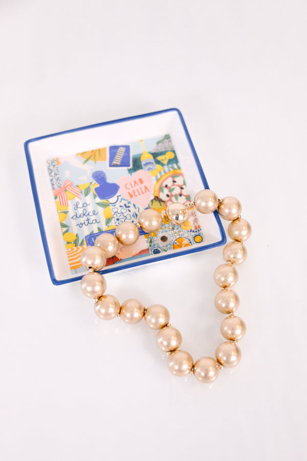 A timeless necklace featuring large, cascading gold statement beads with a warm metallic finish.