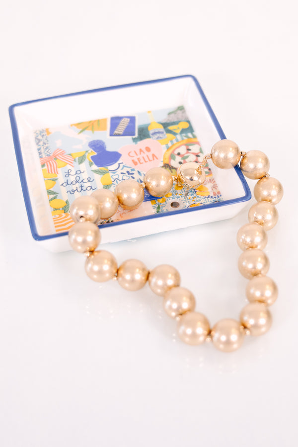 A timeless necklace featuring large, cascading gold statement beads with a warm metallic finish.